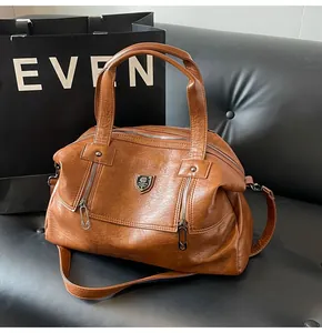 Close-up of vintage brown leather tote bag with metallic logo on a leather sofa
