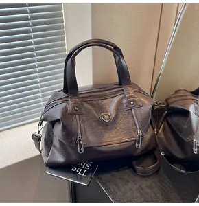 Detailed close-up of dark brown vintage leather Boston bag with double zippers and metal logo