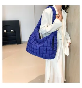 Model met een grote koningsblauwe gewatteerde shopper met elegant ruitjespatroon
