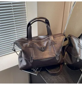 Detail of dark brown vintage faux leather tote with metal shield and vertical zippers