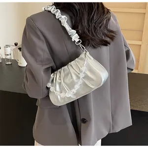 Detail van zilveren geplooide cloud bag met elastische riem en kralenketting