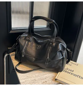 Detail of a black Boston bag with unique paperclip zipper pull and metal shield logo