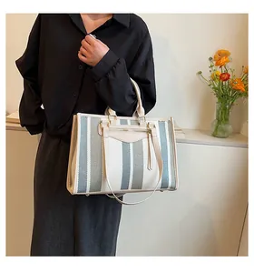 Detail van grijsgroene gestreepte canvas shopper met beige leren bies en gouden rits