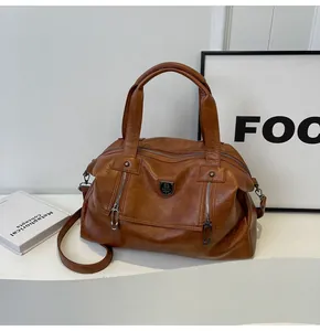 Detail of vintage brown PU leather tote with dual zippers and metallic shield ornament