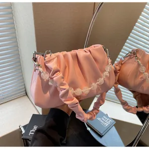 Detailweergave van de roze geplooide tas met decoratieve transparante kralenketting