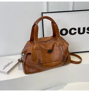 Close-up of brown PU leather bag featuring double vertical zippers and metal shield logo