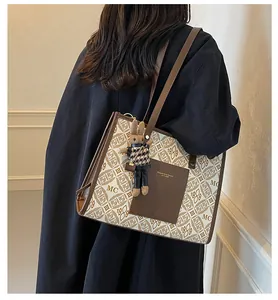 Detailed view of monogram tote bag featuring a leather patch and cute plush rabbit charm