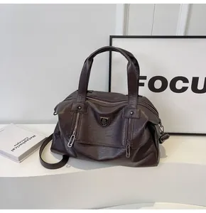 Close-up of dark brown soft leather tote bag with vertical zippers and metal shield logo