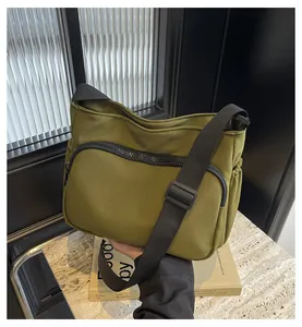 Détail d'un sac bandoulière en nylon vert olive avec sangle réglable et cordons latéraux