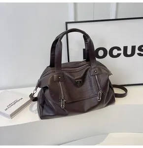 Detail of dark brown leather tote bag featuring vertical zippers and embossed shield logo