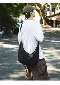 Rear view of black nylon dumpling bag showing large capacity and crossbody fit on a person
