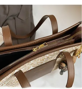Close-up of smooth gold zipper and premium leather trim on beige monogram tote bag