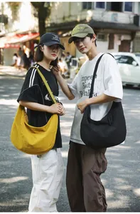 Street style view of two models wearing oversized nylon crossbody bags in yellow and black