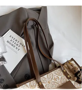 Close-up of canvas tote bag featuring leaf pattern, leather handles and bear charm