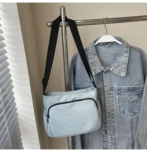 Détail du sac bandoulière en nylon bleu clair avec poche zippée et sangle réglable