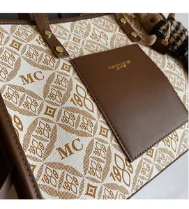 Close-up of leather tote bag featuring monogram print, outer pocket, and plush bear charm