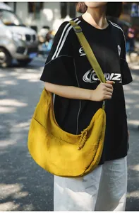 Macro detail of yellow nylon dumpling bag with adjustable green strap and front pockets