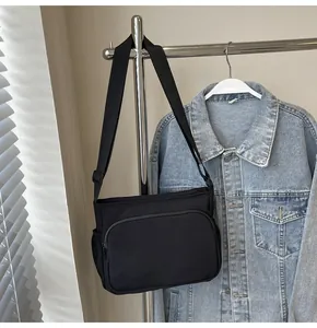 Détail d'un sac bandoulière en nylon noir avec poche zippée et sangle réglable
