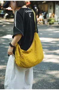 Yellow nylon dumpling cross-body bag featuring front pockets and adjustable strap for outdoors