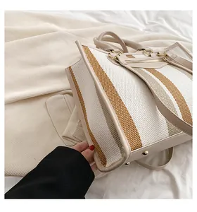 Detailopname van gestreepte canvas shopper met leren bies en gouden metalen ringen