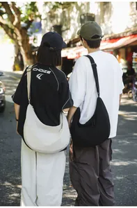 Outdoor shot of models wearing black and off-white nylon dumpling bags in urban style