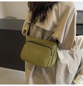Détail du sac bandoulière en nylon vert olive montrant la sangle réglable au dos