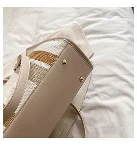 Detail van de beige lederen bodem met gouden noppen op de gestreepte canvas tas