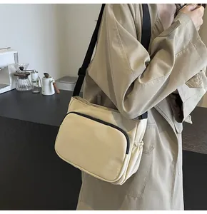 Détail latéral d'un sac bandoulière beige en nylon avec poche zippée et poche latérale à cordon