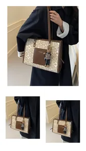 Detail view of vintage tote bag with monogram pattern, brown leather pocket and rabbit charm