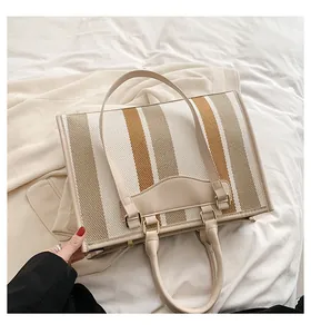 Detail van de gestreepte canvas tote bag met lederen riemen en metalen gespen