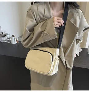 Détail d'un sac bandoulière minimaliste en nylon beige avec large sangle noire