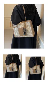 Detail of beige monogram tote bag with brown leather trim and cute rabbit pendant charm