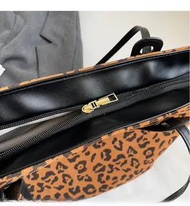 Close-up of golden smooth zipper and grey herringbone lining on leopard print tote bag