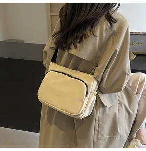 Détail d'un sac bandoulière en nylon crème avec fermeture éclair noire contrastée