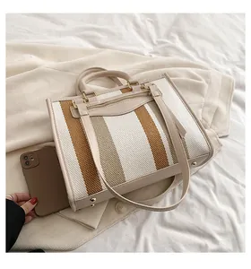 Detail van de gestreepte canvas shopper met lederen biezen en metalen nopjes op de bodem