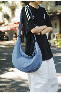 Detail of misty blue nylon dumpling bag showing pleated texture and wide shoulder strap