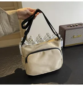 Détail du sac bandoulière en nylon beige avec fermeture éclair et poche latérale élastique