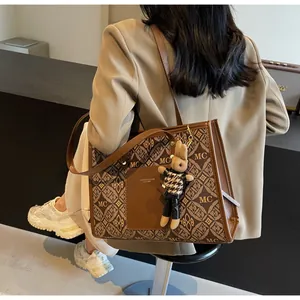 Detail view of large brown tote bag with vintage monogram print and rabbit charm accessory
