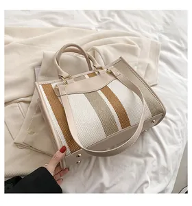 Detail van gestreepte canvas tas met leren bies, metalen noppen en schouderband