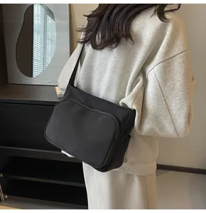 Détail d'une sacoche en nylon noir avec double fermeture éclair et bandoulière large