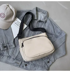 Détail du sac bandoulière en nylon beige avec double zip et bandoulière noire