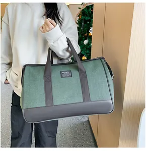 Detail of dark green canvas travel bag with leather handles held by a model in a cozy setting