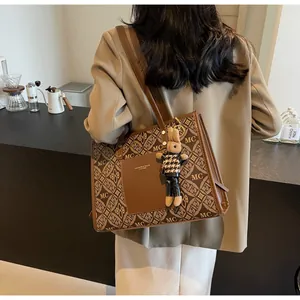 Detail of vintage brown tote bag with logo print, leather pocket and plush bunny charm