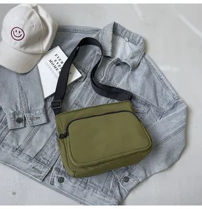 Détail d'un sac bandoulière en nylon vert olive sur un fond lifestyle décontracté