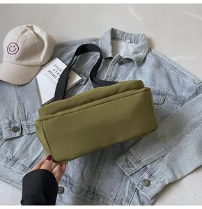 Détail du sac bandoulière en toile vert armée avec sangle noire et accessoires