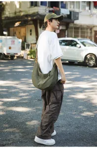 Close-up of olive green nylon dumpling bag with adjustable strap in street setting