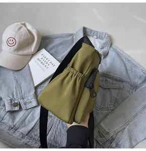 Détail de sac bandoulière en nylon vert olive montrant la poche latérale et la fermeture noire