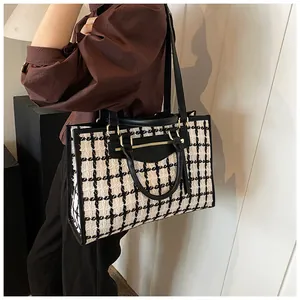 Detail view of large plaid tweed tote bag with black leather handles and metal hardware