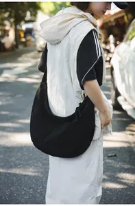 Close-up of black nylon hobo bag featuring wide strap and textured fabric in sunlight