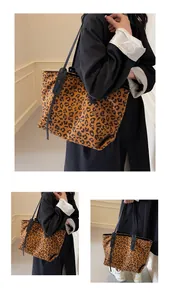 Close-up of a large leopard print tote bag with black straps on a woman's shoulder